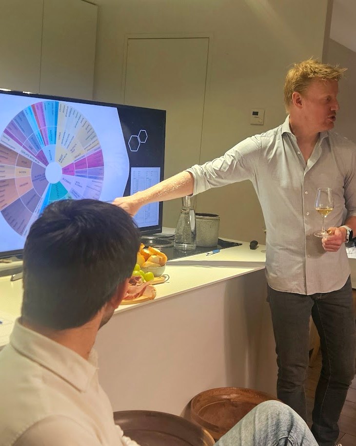 Tim tijdens een wijnworkshop, wijzend naar het aromawiel op het scherm